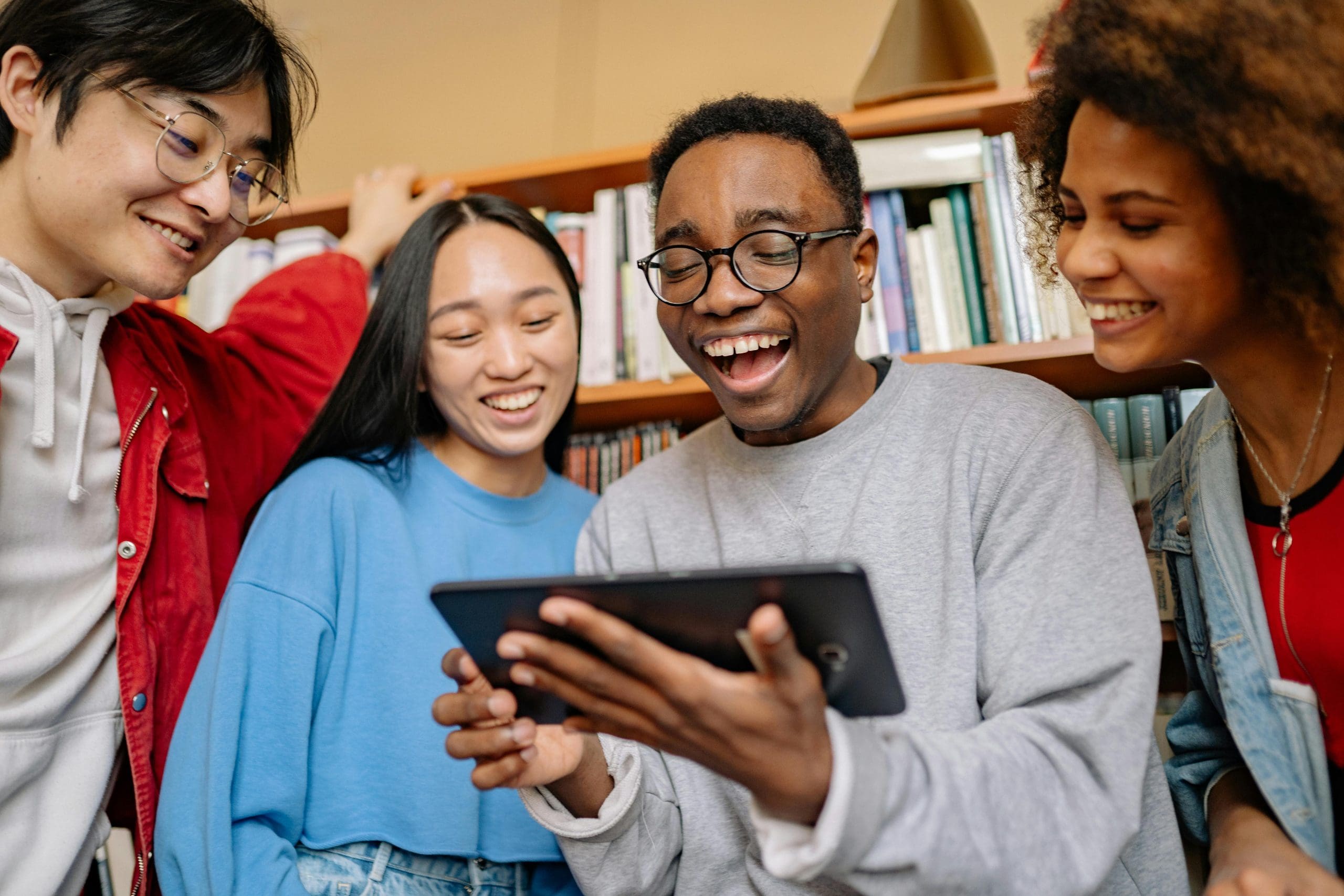 college students looking at an ipad together in a library