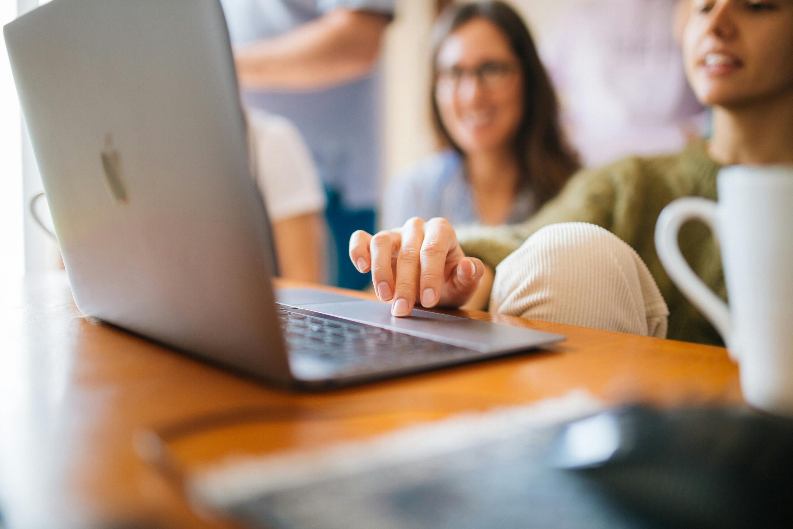 People looking at a laptop together Two people looking at a laptop together drinking coffee