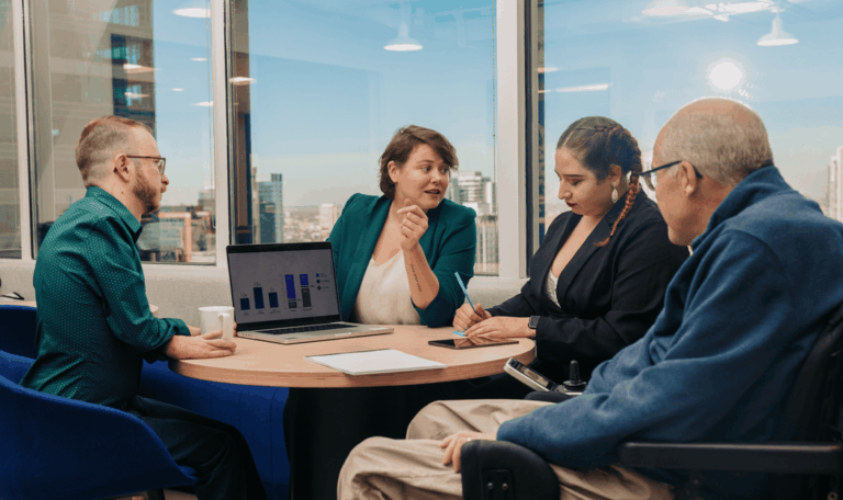 a small groupd of colleagues working together at a table in front of a window