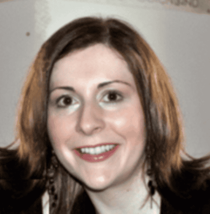 person with short redish brown hearing smiling