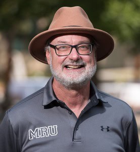 person wearing a tan hat and glasses smiling